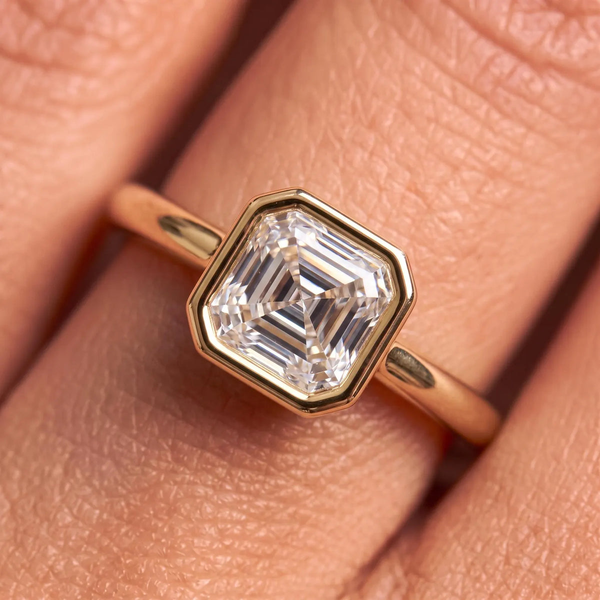 Macro detail shot of bezel-set Asscher cut lab diamond ring on finger