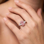 Hand model wearing pink diamond engagement ring near collarbone