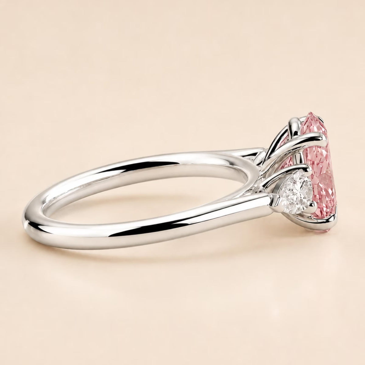 Side profile view of white gold three-stone ring with pear side stones
