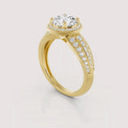 A yellow gold ring with a round-cut diamond center stone, a halo of small diamonds, and a split shank paved with diamonds, shown on a light gray background.