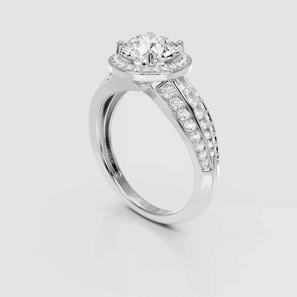 A silver-toned diamond ring with a round-cut center stone, a halo of smaller diamonds, and a split shank paved with diamonds, shown on a light gray background.