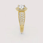 A yellow gold engagement ring featuring a large round-cut center stone and pavé-set diamond bands, shown on a light gray background.