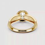 A polished yellow gold ring with a unique bow-like split band design and a single clear gemstone in the center, shown on a light gray background.