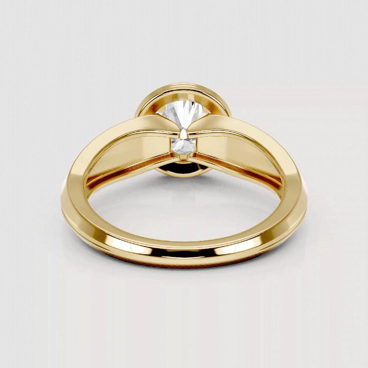 A polished yellow gold ring with a unique bow-like split band design and a single clear gemstone in the center, shown on a light gray background.