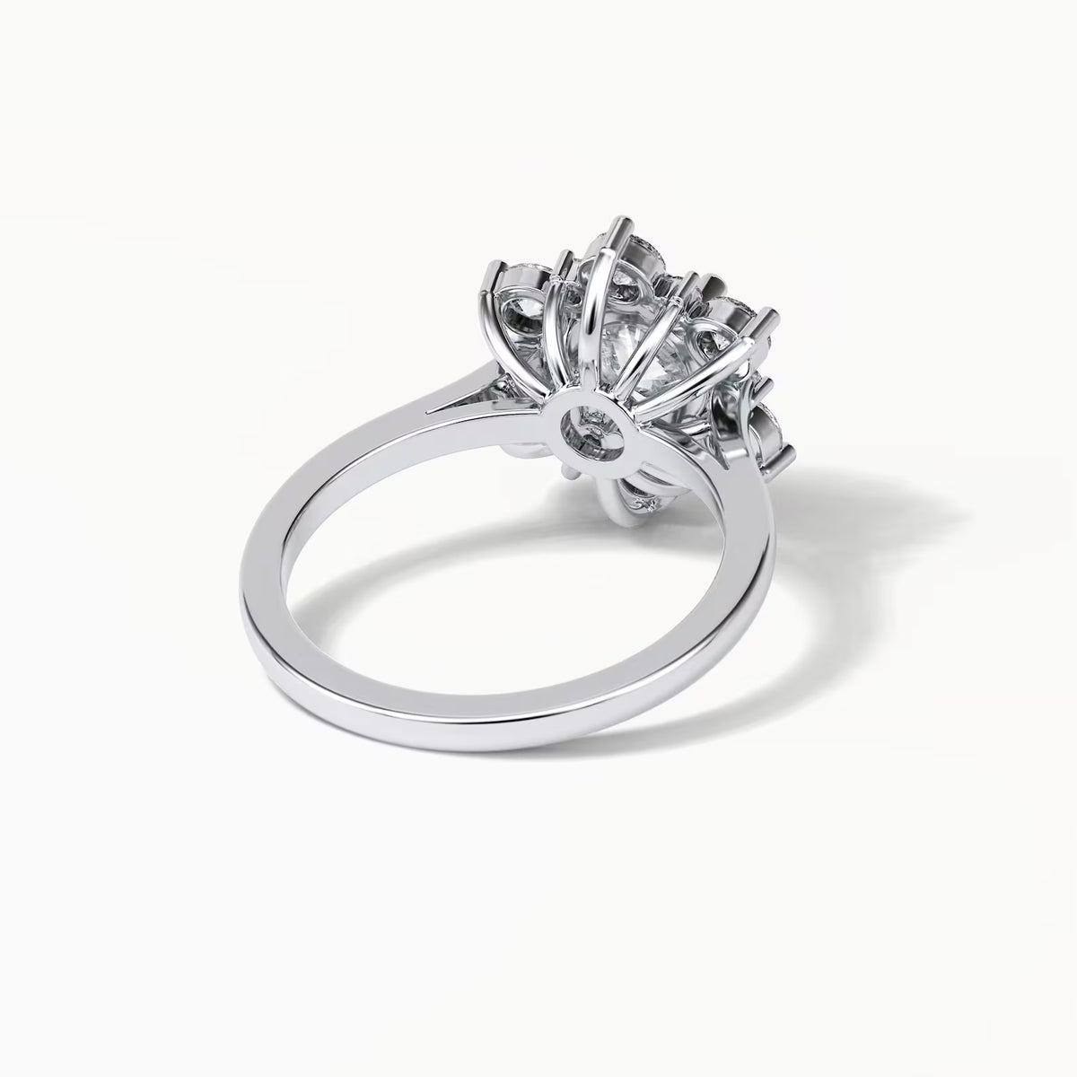A silver-toned ring with a large, intricate floral or starburst cluster setting, photographed on a clean white background with a soft shadow.