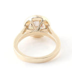 Under-gallery perspective showing the open basket setting of a 3 CT round lab diamond bezel ring in yellow gold.