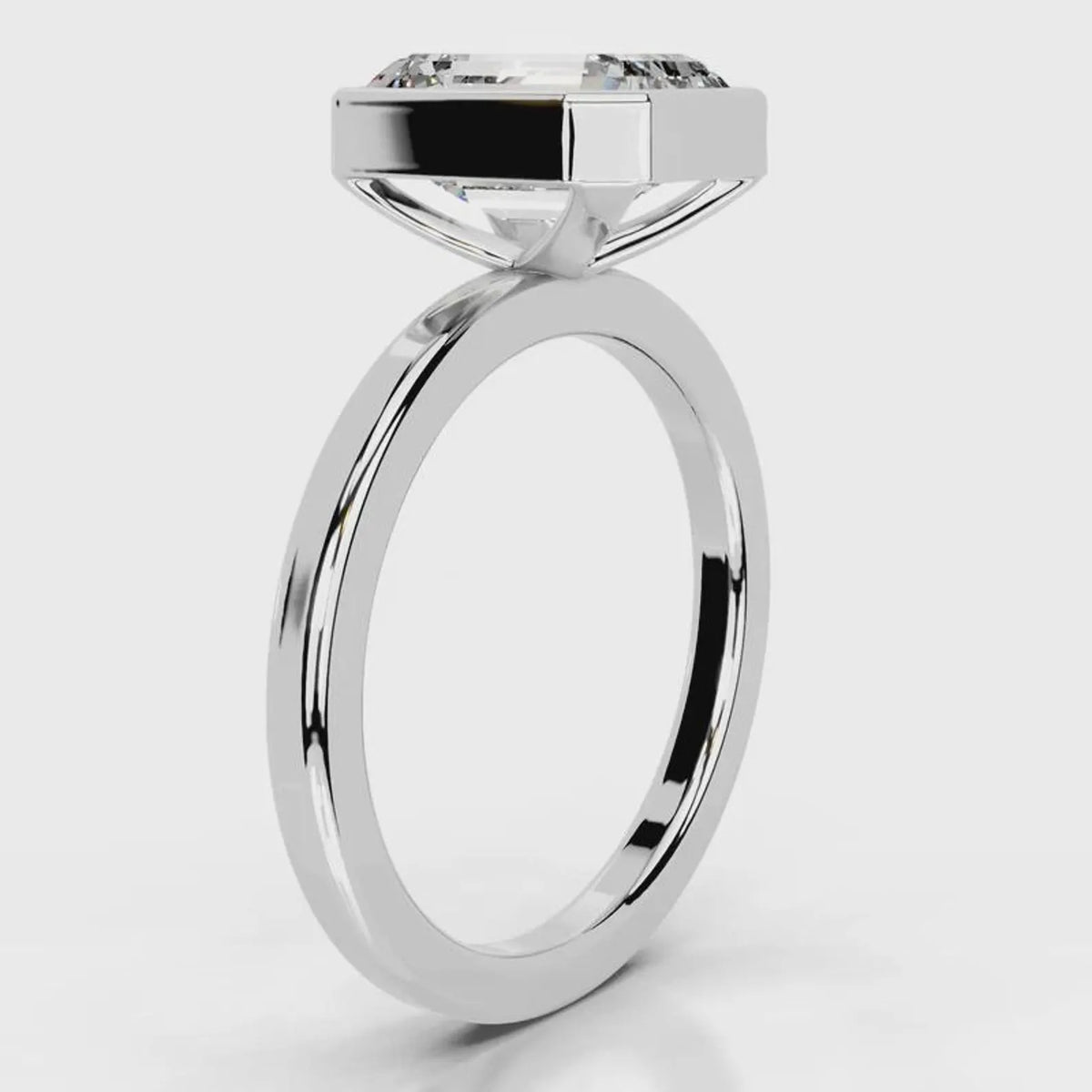 Side profile view of a 4 CT emerald cut lab grown diamond bezel engagement ring in white gold.