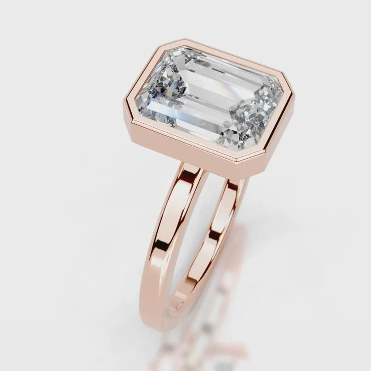 Angled top view showing the step cut facets of a 4 CT emerald lab diamond bezel ring in rose gold.