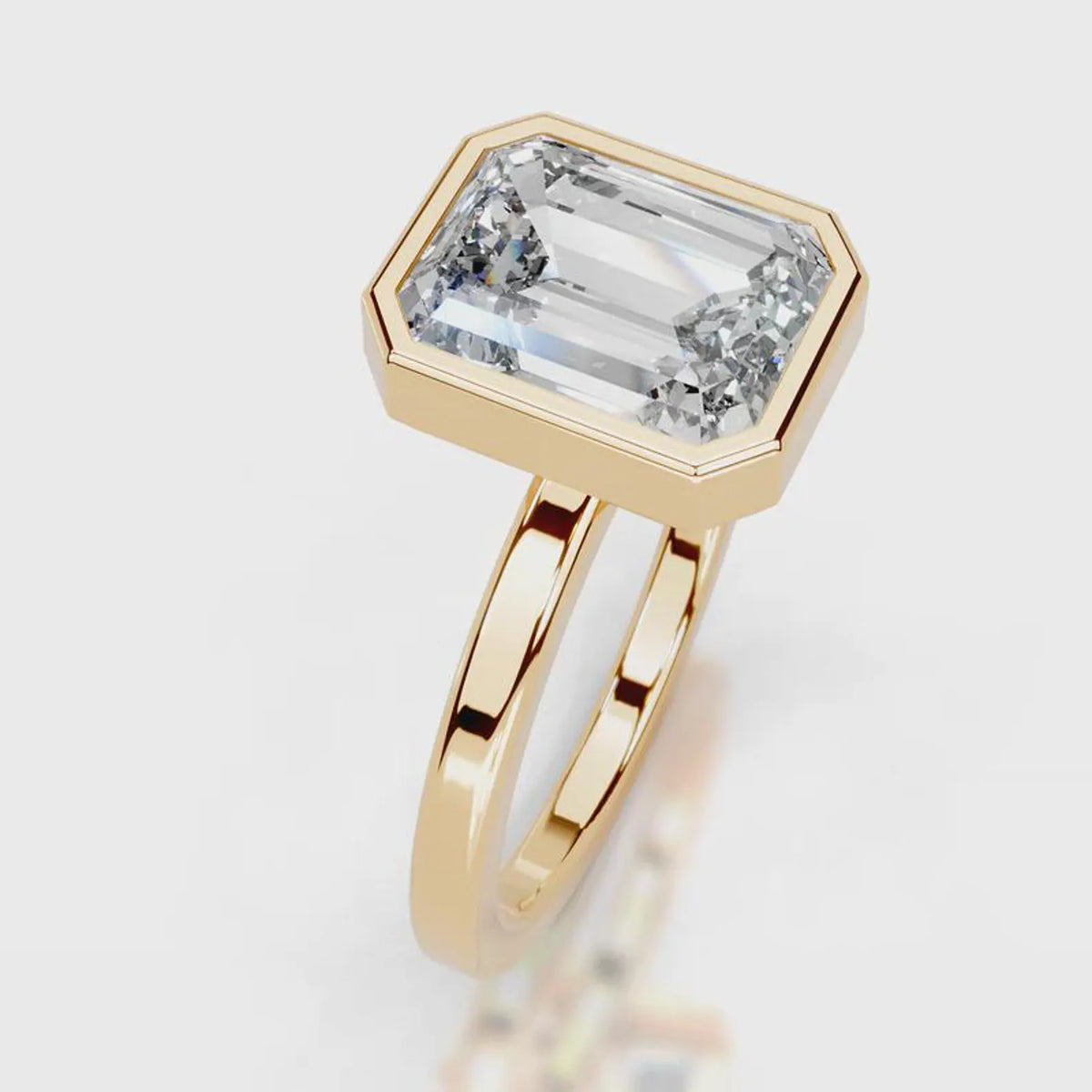 A gold ring featuring an oversized, beveled emerald-cut clear gemstone, shown on a clean white background with a soft reflection.