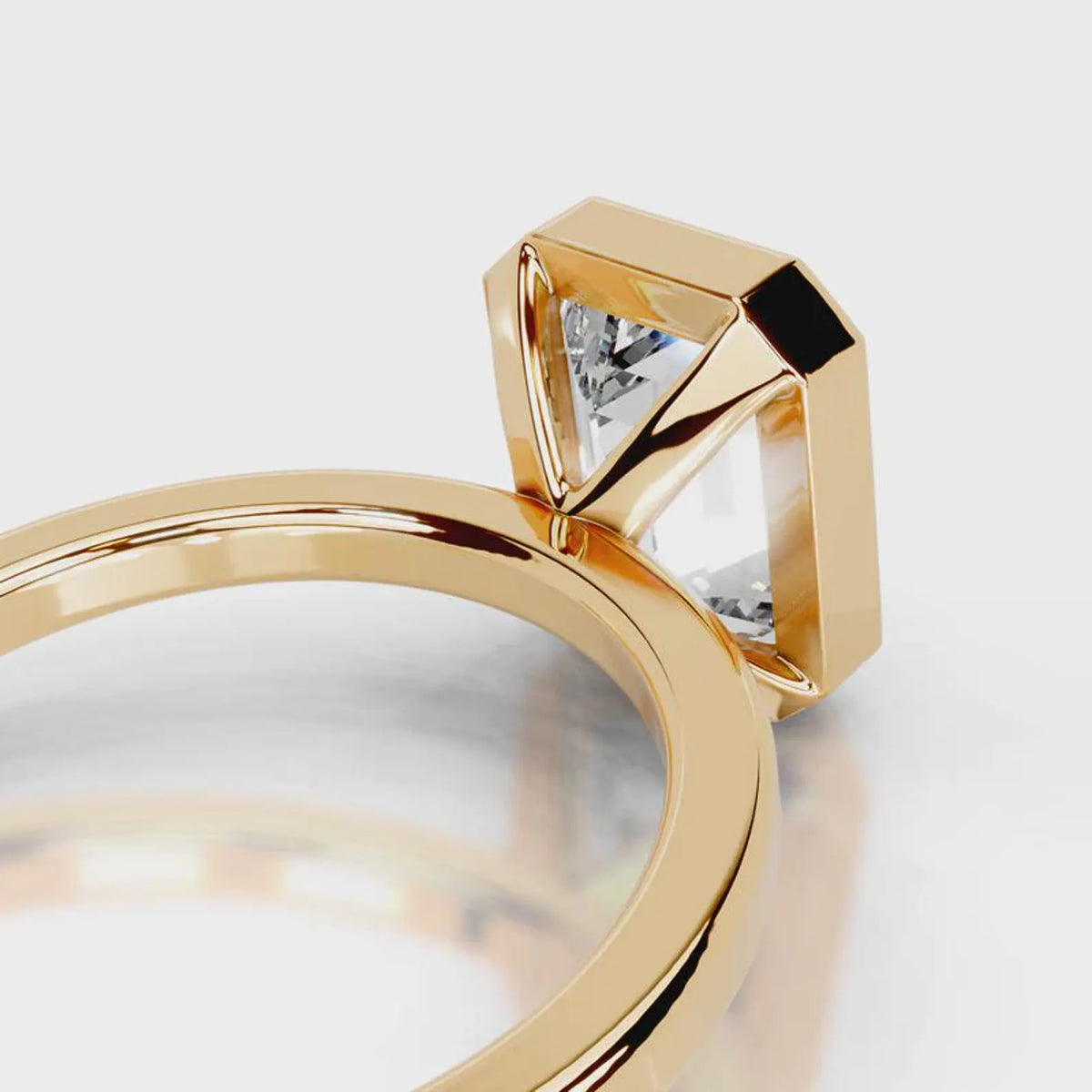 Architectural open basket detail of a 4 CT emerald cut lab diamond bezel ring in yellow gold