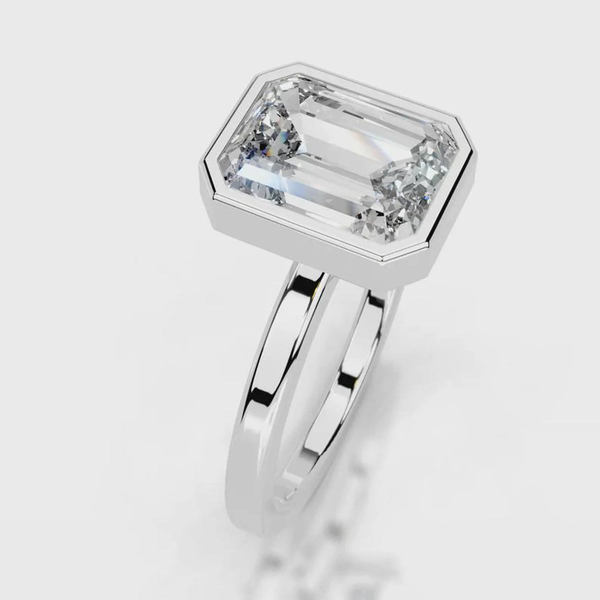 Three-quarter angle view of a 4 CT emerald cut lab grown diamond bezel ring in white gold.