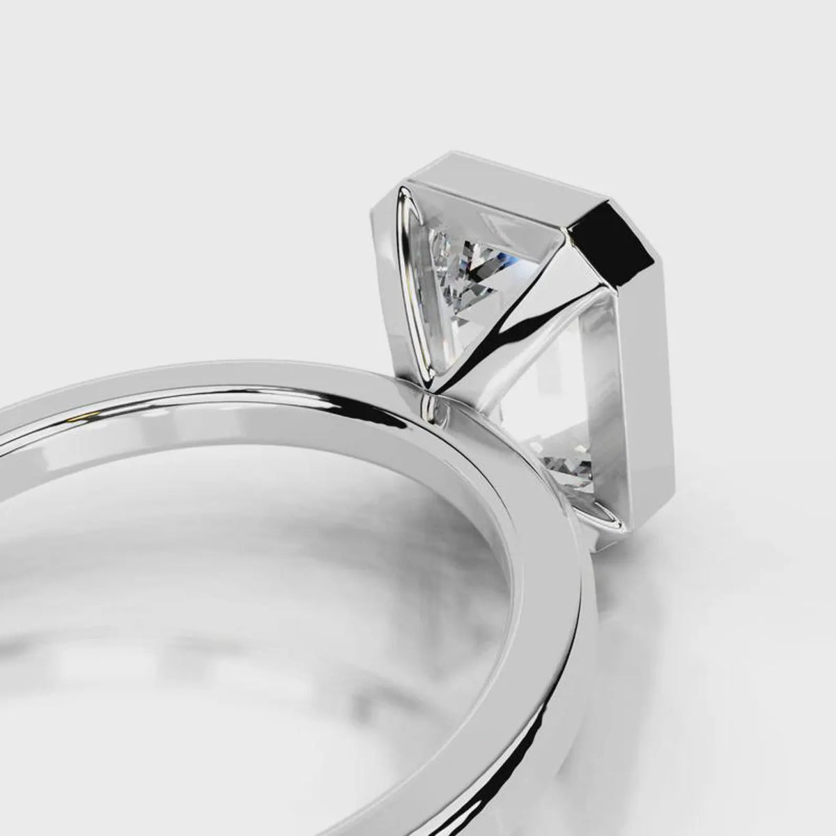 Under-gallery profile of a 4 CT emerald cut lab diamond solitaire ring with bezel frame in white gold.