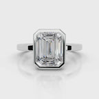 Front view of a 4 CT step cut emerald lab diamond set in a smooth white gold bezel frame.