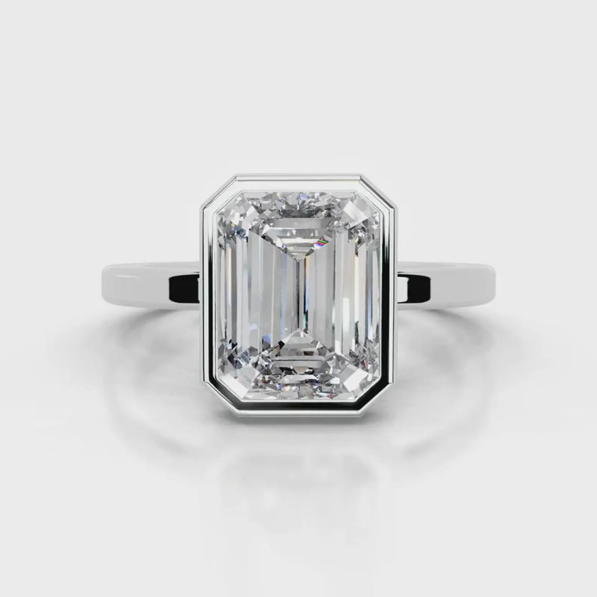 Front view of a 4 CT step cut emerald lab diamond set in a smooth white gold bezel frame.