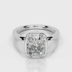 A radiant cut diamond engagement ring in a polished silver-colored metal band, shown on a clean light gray background with a soft reflection.