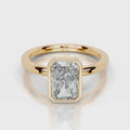 A yellow gold ring featuring a large, bezel-set rectangular emerald-cut diamond. The diamond is clear and does not contribute to the color mapping according to the schema rules, so the product color is determined solely by the gold metal band.