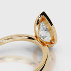 Close-up view of open gallery cut-out detail on 4 CT pear lab diamond ring in yellow gold.