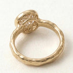 Underside view of a yellow gold bezel ring revealing an intricate floral filigree undergallery supporting a 3 carat round lab grown diamond.