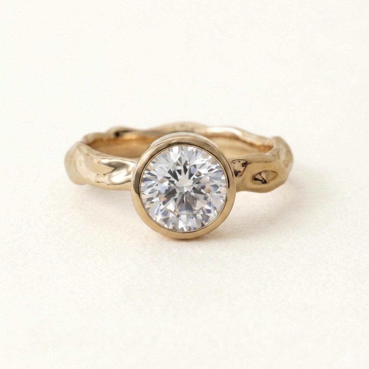 Top-down front view of a sparkling 3 carat round brilliant lab grown diamond in a smooth gold bezel with textured band.