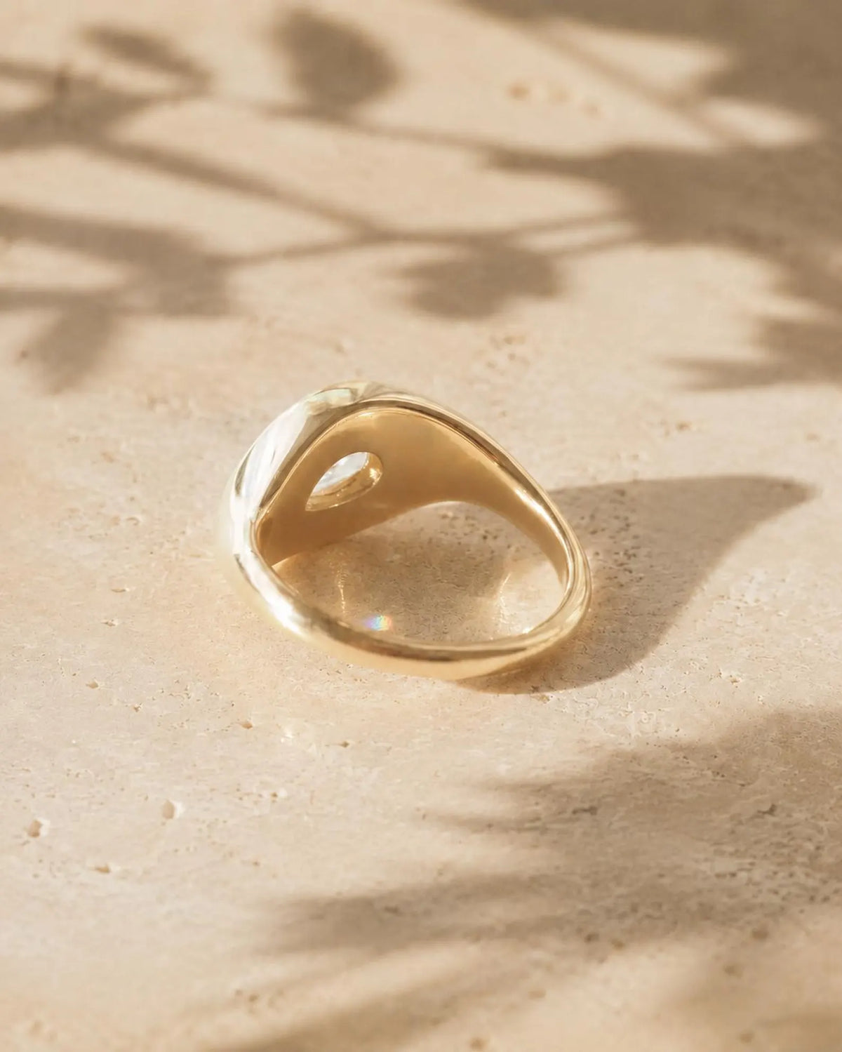 Underside view of a solid yellow gold chunky bezel ring showing the teardrop cutout for a 2 carat pear lab diamond.