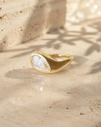 Side profile angle of a smooth, sculptural yellow gold dome band featuring a flush-set pear cut lab diamond.