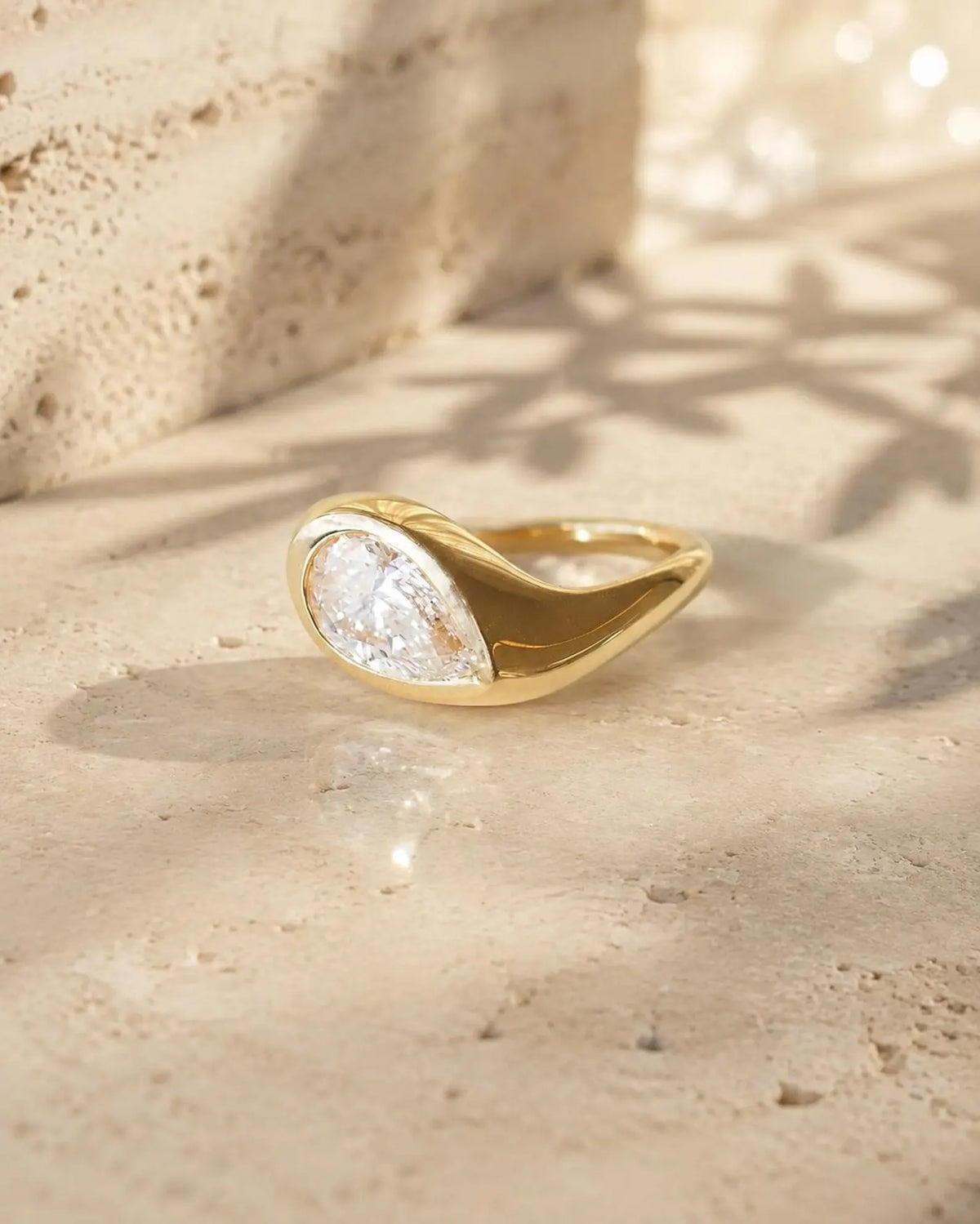 Side profile angle of a smooth, sculptural yellow gold dome band featuring a flush-set pear cut lab diamond.