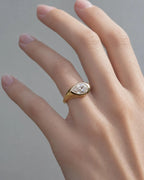 On-hand view of a modern 2 carat pear cut lab grown diamond chunky bezel signet ring on a woman's finger.