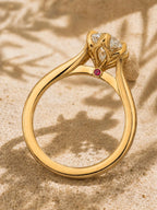 Inside profile view of a yellow gold engagement ring showing a hidden flush-set red ruby accent on the inner bridge.