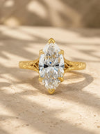 Top-down front view of a 4 carat marquise cut lab grown diamond in a 6-prong yellow gold setting with hand-carved shoulders.