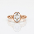 Front view of a 3 carat oval lab grown diamond bezel engagement ring in rose gold with botanical leaf engraving.