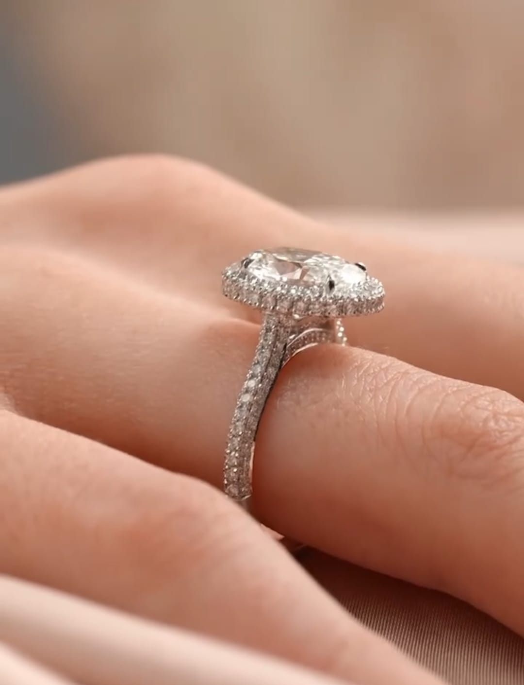 Side perspective view on finger showing the raised cathedral basket and sparkling pavé shank of an oval lab diamond ring.