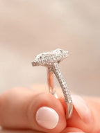 Side profile held in fingers showcasing the slender pavé diamond band and low-profile halo.