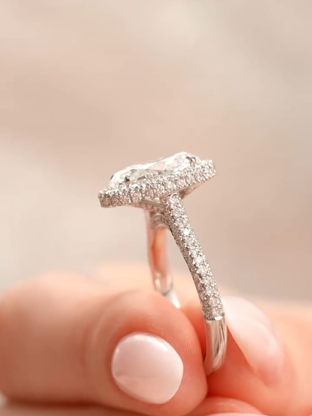 Side profile held in fingers showcasing the slender pavé diamond band and low-profile halo.