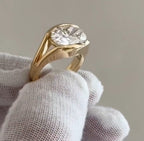 Perspective side view showing the thick 18K yellow gold band and low profile bezel setting of a 4 ct oval lab diamond ring.