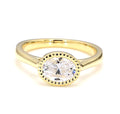 Top-down view of a 2 CT oval cut lab grown diamond set horizontally in a yellow gold milgrain bezel ring.