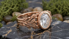Three-quarter angle of rose gold leaf engagement ring on dark marble background.