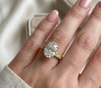 Close-up on-hand photo of 4 CT oval lab diamond engagement ring with antique engraved band.