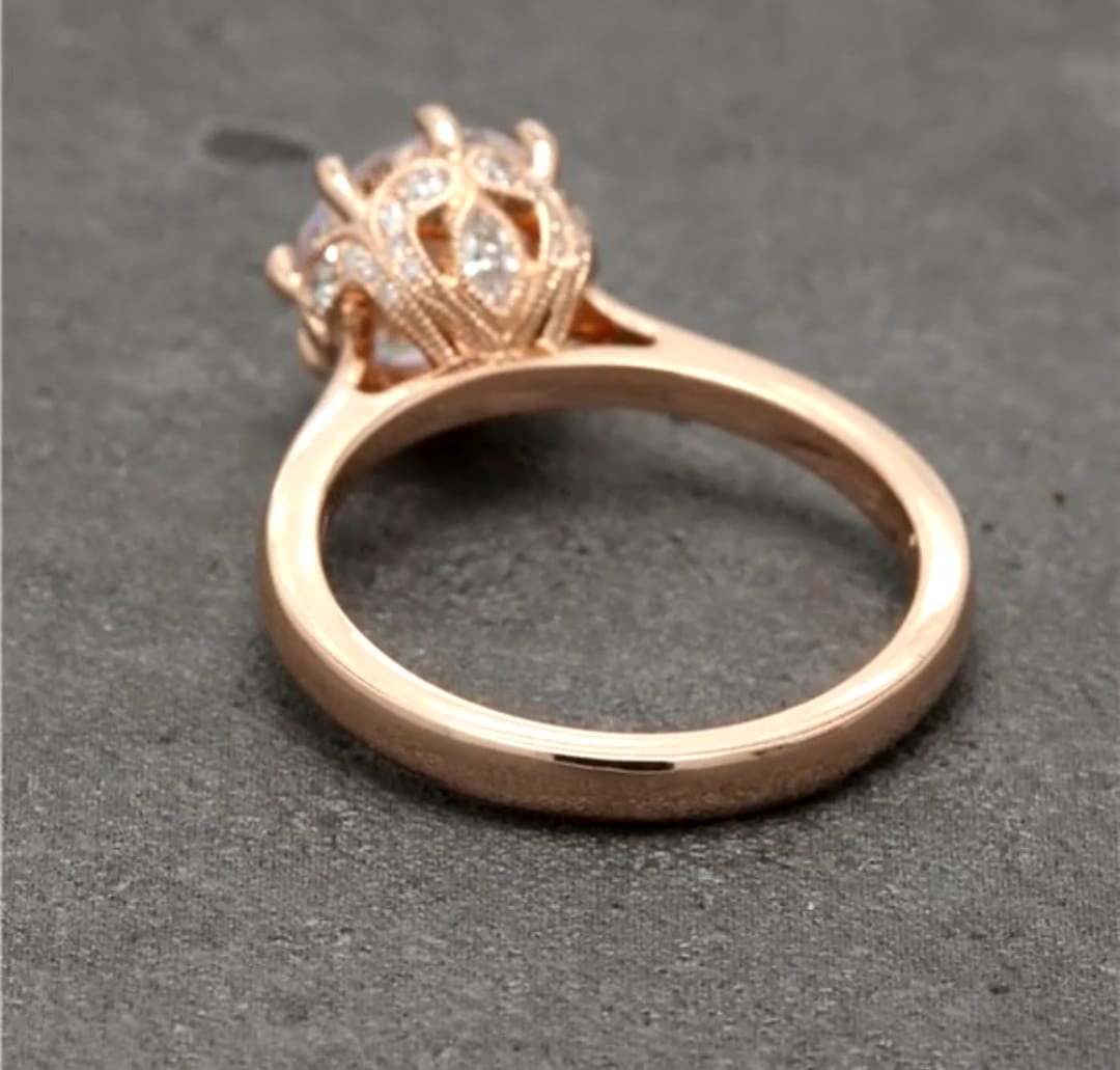 Angled under-gallery detail showing the crown-inspired filigree setting with accent diamonds in rose gold.