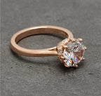 Alternate three-quarter angle displaying the round brilliant center stone and warm rose gold mounting.