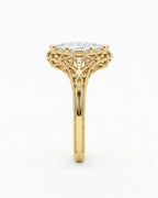 Side profile view of a 4 CT marquise lab grown diamond ring showing yellow gold openwork scrollwork undergallery.