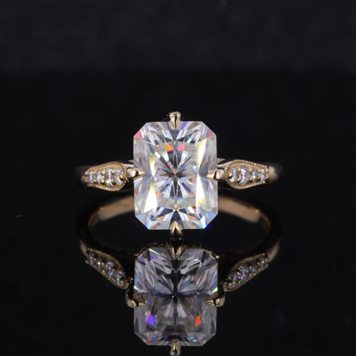 Top face-up view of a 2 CT radiant cut lab diamond ring featuring milgrain-detailed leaf shoulders on a reflective black background.