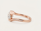 Side profile view of a 3 CT East-West oval lab grown diamond bypass engagement ring in rose gold with pavé accent diamonds