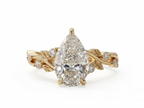 Top-down view of a 3 CT pear cut lab grown diamond nature inspired ring in yellow gold with leaf and diamond accents.