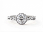 Top-down view of a 3 carat round cut lab grown diamond set in a white gold milgrain bezel ring.
