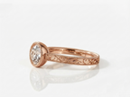 Side view showing engraved leaf details on a rose gold 3 CT round lab diamond bezel ring.