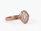 Perspective view of a rose gold 3 CT oval lab grown diamond engagement ring with milgrain bezel and filigree band.
