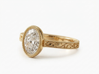 Angled perspective of a 3 CT oval cut lab diamond engagement ring in yellow gold with beaded bezel setting.