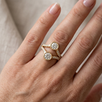 On-hand perspective of a yellow gold two stone round lab diamond bezel ring on finger.