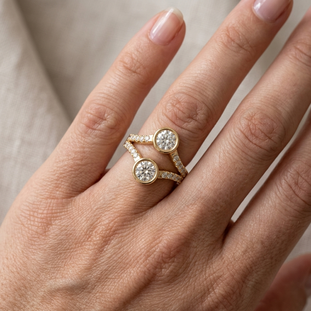 On-hand perspective of a yellow gold two stone round lab diamond bezel ring on finger.