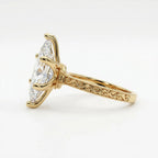 Angled side view of a 4 carat marquise cut lab diamond solitaire ring displaying carved scroll pattern with milgrain edges.